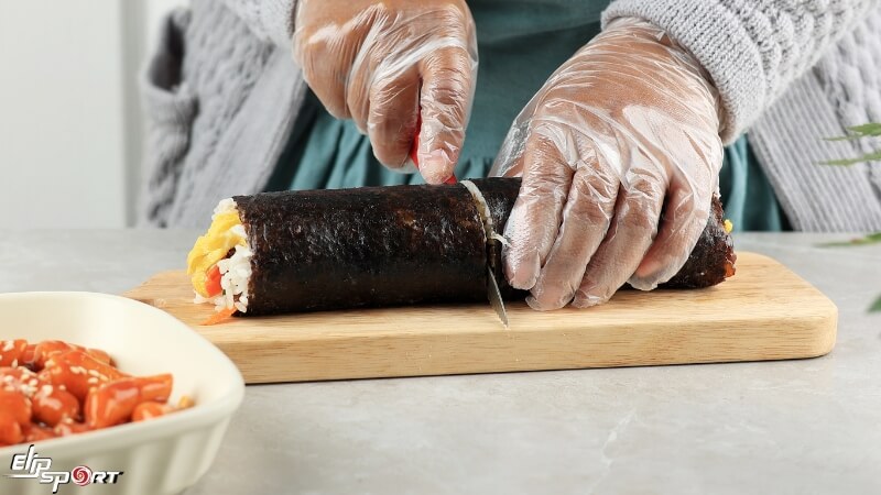 Cuộn kimbap v&agrave; cắt th&agrave;nh miếng vừa ăn
